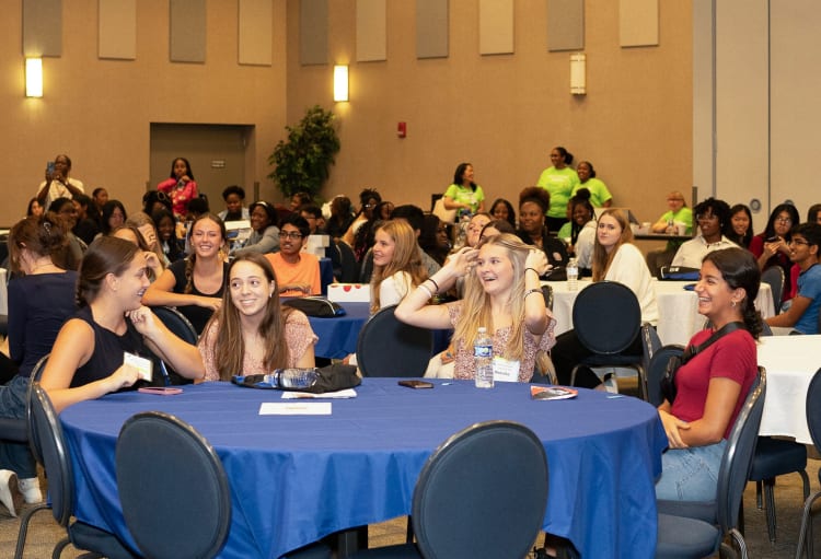 smiling teenagers sit together at a table during the health care career conference